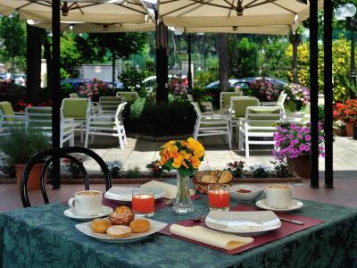 Colazione all'aperto con caffè, succo e dolci, circondata da fiori e verde.