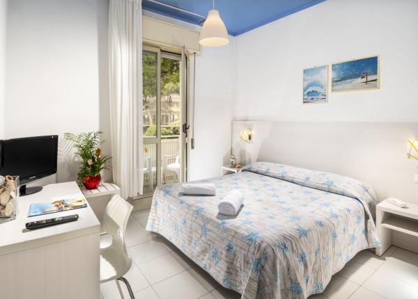 Bright room with double bed, balcony, TV, and marine-themed decor.